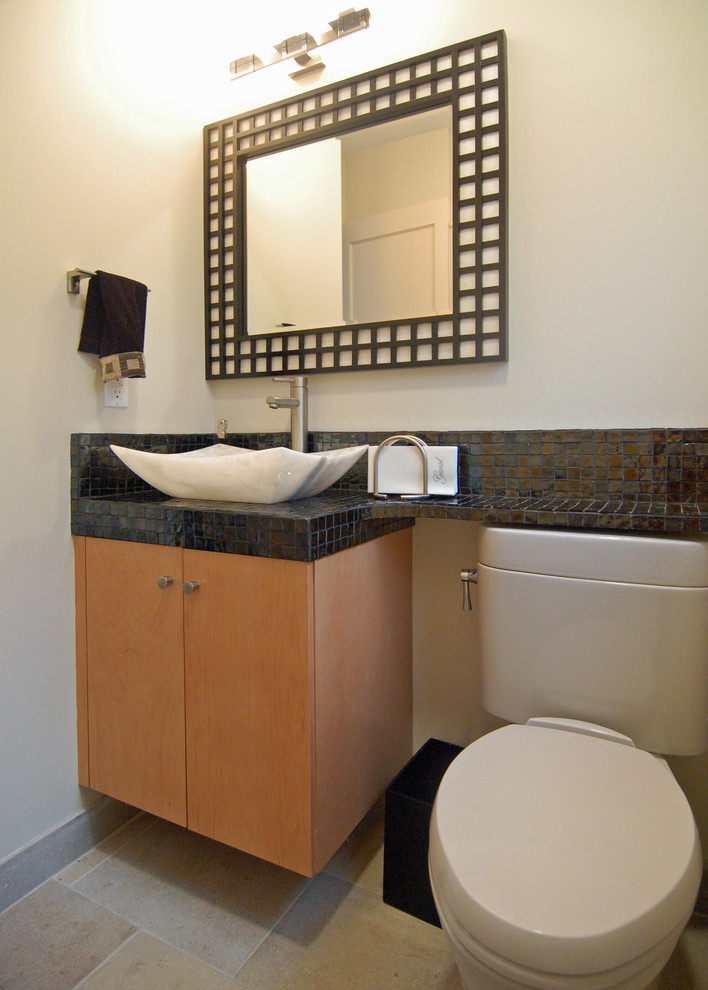 Foto på ett litet badrum med dusch, med ett fristående handfat, släta luckor, skåp i ljust trä, kaklad bänkskiva, en toalettstol med separat cisternkåpa, svart kakel, glaskakel, vita väggar och travertin golv