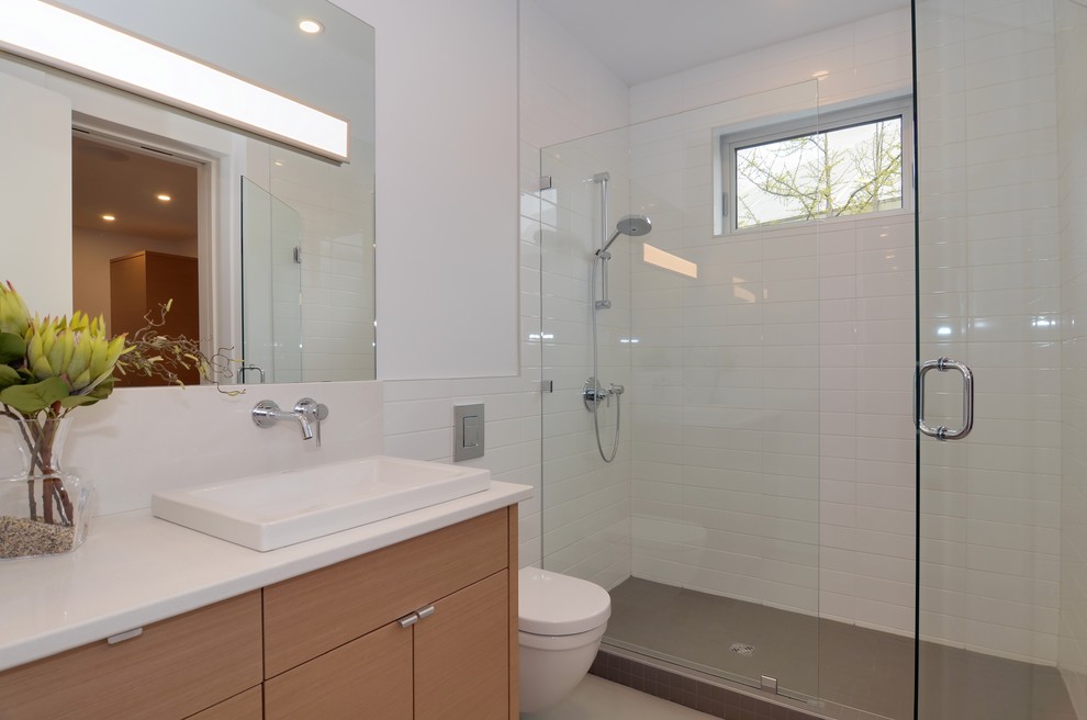 Bild på ett mellanstort skandinaviskt badrum med dusch, med ett fristående handfat, släta luckor, skåp i ljust trä, bänkskiva i kvarts, en öppen dusch, en vägghängd toalettstol, vit kakel, keramikplattor, vita väggar och betonggolv