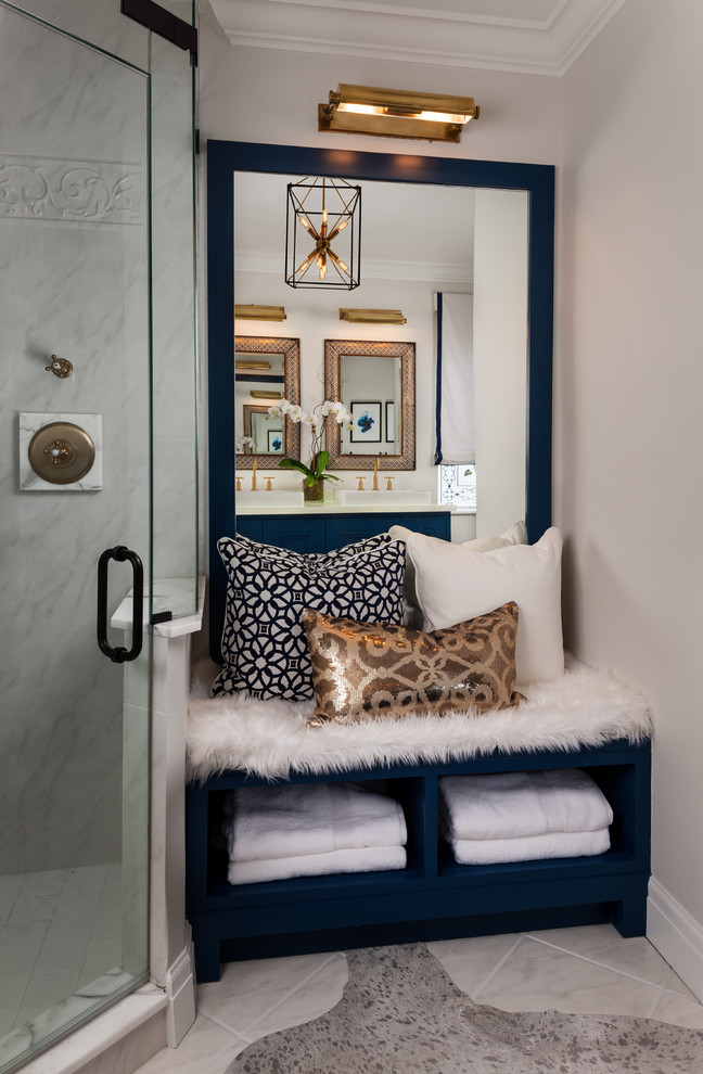 Cette photo montre une salle de bain principale chic de taille moyenne avec une vasque, un placard en trompe-l'oeil, des portes de placard bleues, une baignoire d'angle, une douche d'angle, un carrelage blanc, un carrelage de pierre, un mur gris et un sol en marbre.