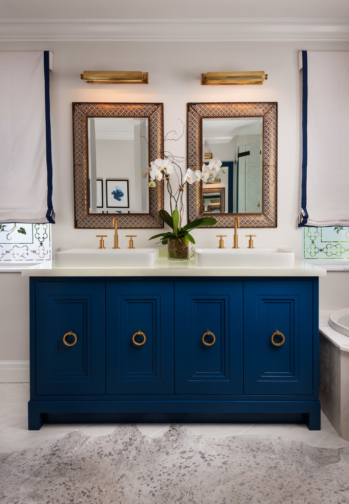 На фото: главная ванная комната среднего размера в стиле неоклассика (современная классика) с настольной раковиной, синими фасадами, накладной ванной, угловым душем, белой плиткой, каменной плиткой, мраморным полом и фасадами с утопленной филенкой