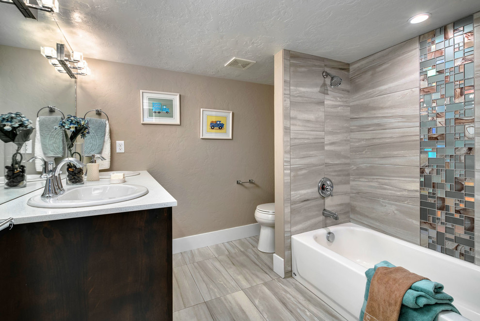 Cette photo montre une petite salle de bain craftsman en bois foncé pour enfant avec un placard à porte shaker, une baignoire en alcôve, un combiné douche/baignoire, WC séparés, un carrelage blanc, des carreaux de porcelaine, un mur gris, un sol en carrelage de porcelaine, un lavabo encastré et un plan de toilette en granite.