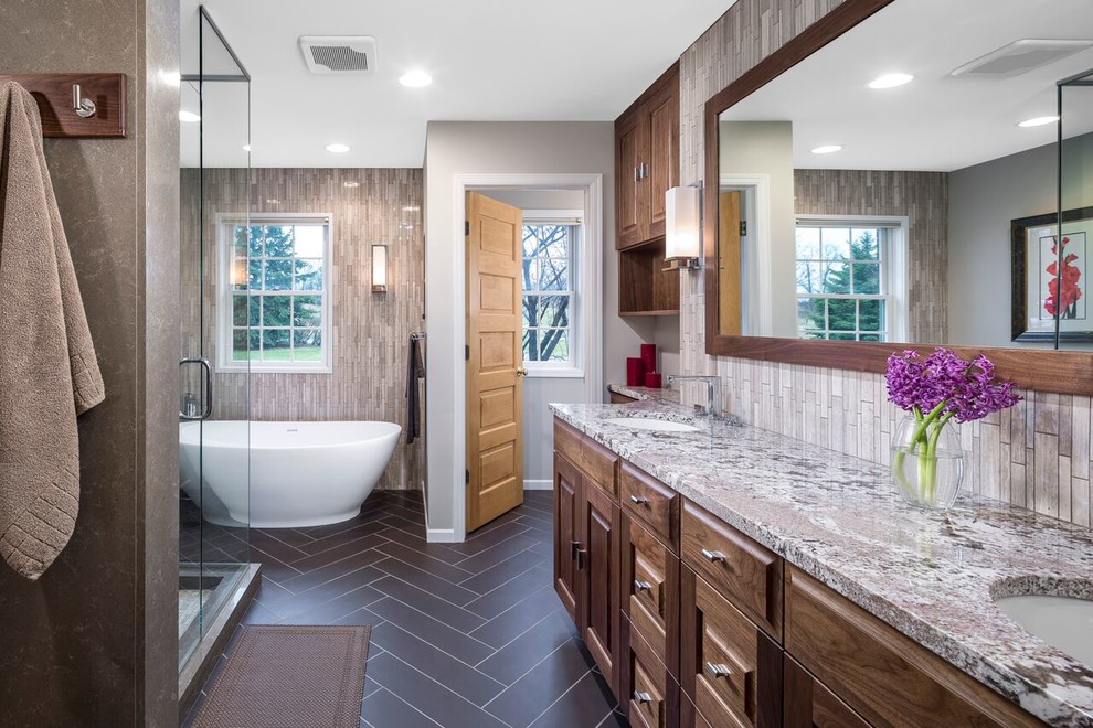 Expansive traditional ensuite bathroom in Minneapolis with medium wood cabinets, a freestanding bath, a corner shower, grey tiles, white walls and a submerged sink.