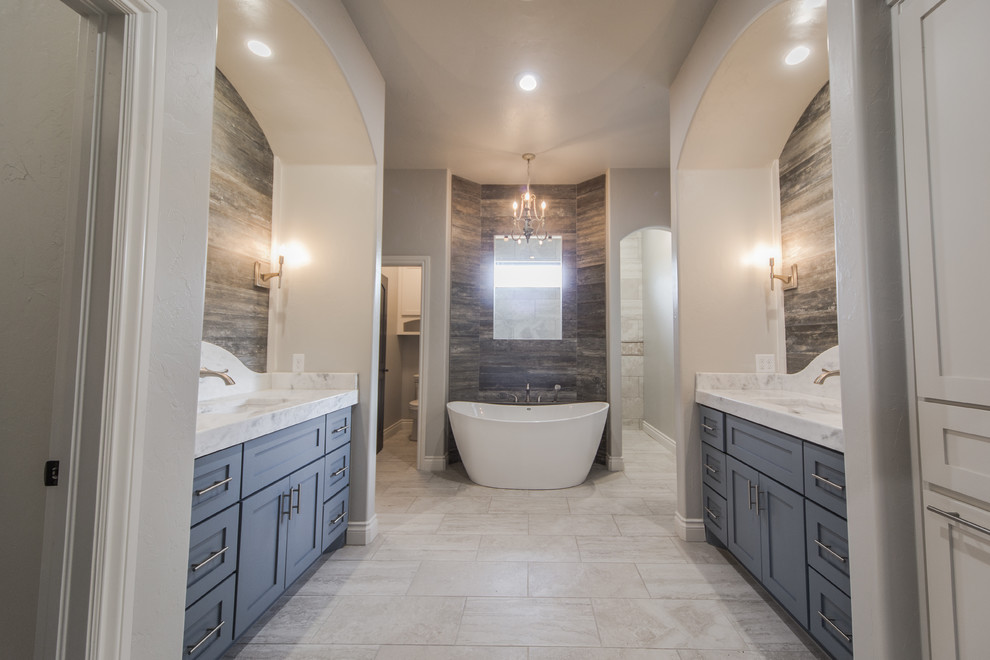 Inredning av ett klassiskt stort en-suite badrum, med skåp i shakerstil, grå skåp, ett fristående badkar, en dusch/badkar-kombination, en toalettstol med separat cisternkåpa, beige kakel, stenkakel, grå väggar, klinkergolv i porslin, ett undermonterad handfat och marmorbänkskiva