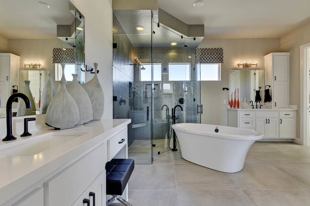 Modern inredning av ett en-suite badrum, med släta luckor, vita skåp, ett fristående badkar, en dubbeldusch, svart kakel, keramikplattor, grå väggar, klinkergolv i porslin, ett avlångt handfat och bänkskiva i akrylsten