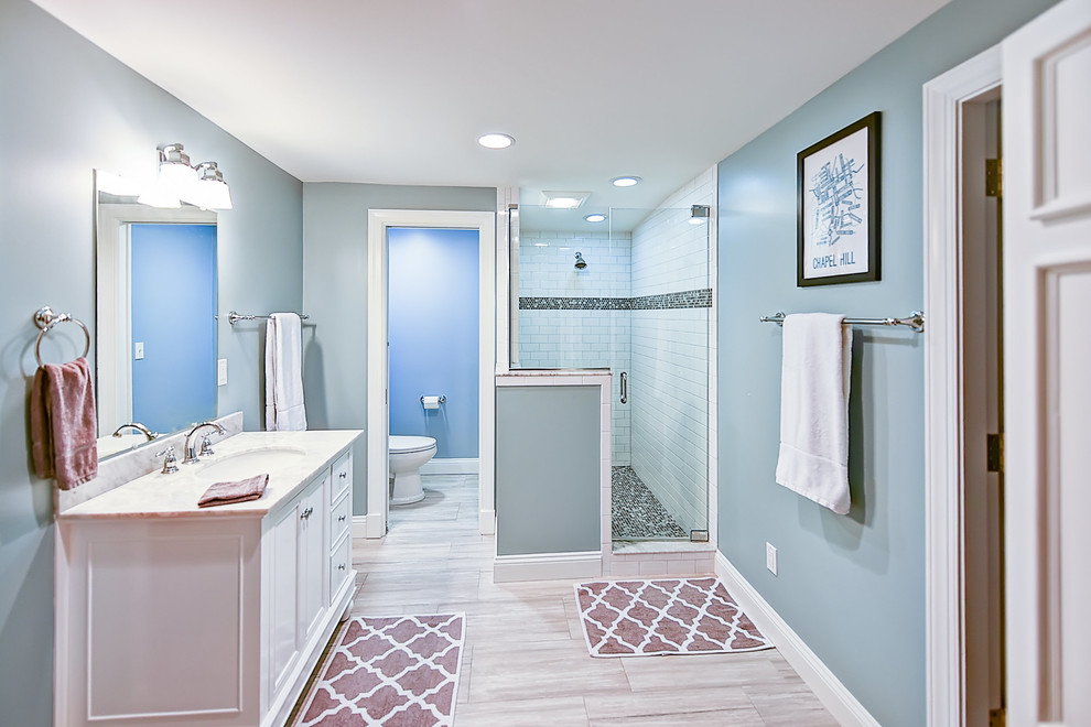 Photo of a large coastal family bathroom in Jacksonville with shaker cabinets, white cabinets, a corner shower, a two-piece toilet, beige tiles, porcelain tiles, blue walls, porcelain flooring and a built-in sink.