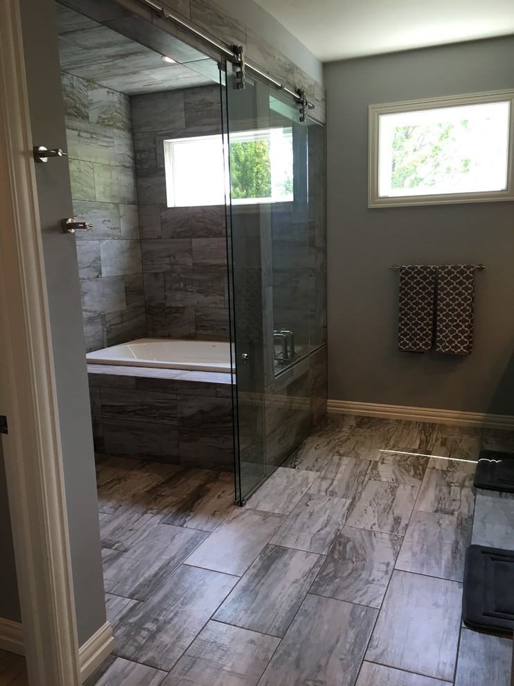 Klassisk inredning av ett stort en-suite badrum, med ett badkar i en alkov, våtrum, grå kakel, keramikplattor, grå väggar, klinkergolv i keramik, grått golv och dusch med skjutdörr