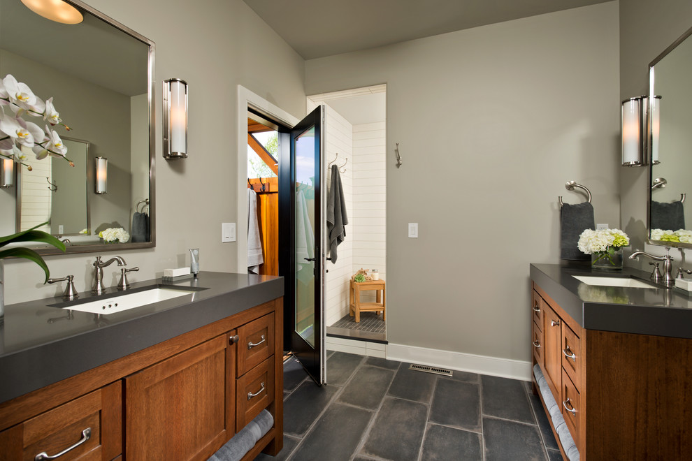 Modelo de cuarto de baño tradicional renovado con puertas de armario de madera oscura, baldosas y/o azulejos grises, paredes grises y lavabo integrado