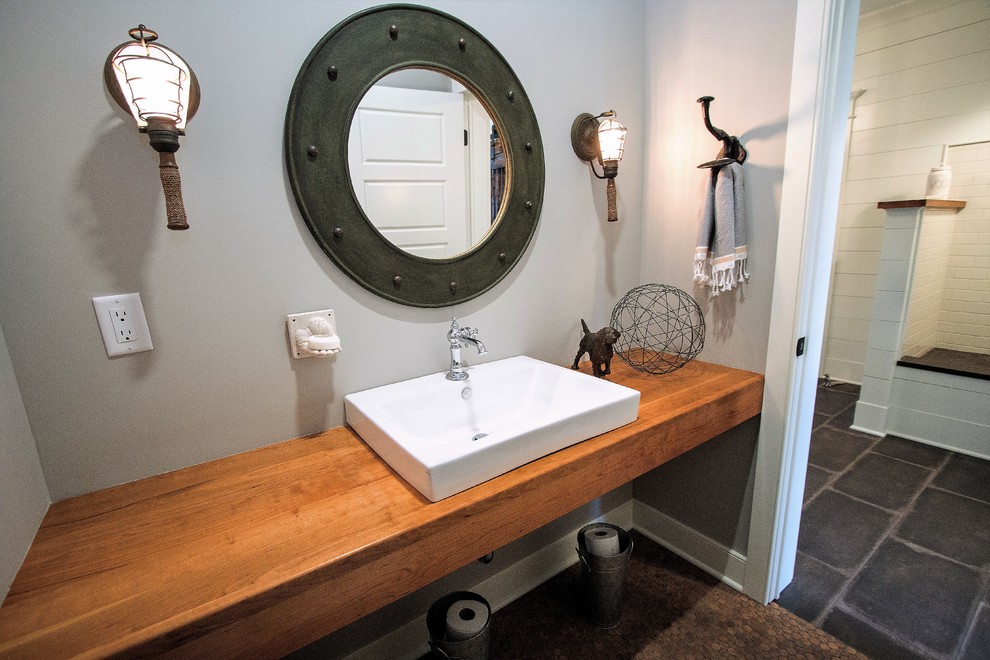 Exempel på ett litet lantligt badrum med dusch, med öppna hyllor, skåp i ljust trä, ett badkar i en alkov, en dusch/badkar-kombination, en toalettstol med separat cisternkåpa, gul kakel, porslinskakel, grå väggar, korkgolv, ett fristående handfat och träbänkskiva