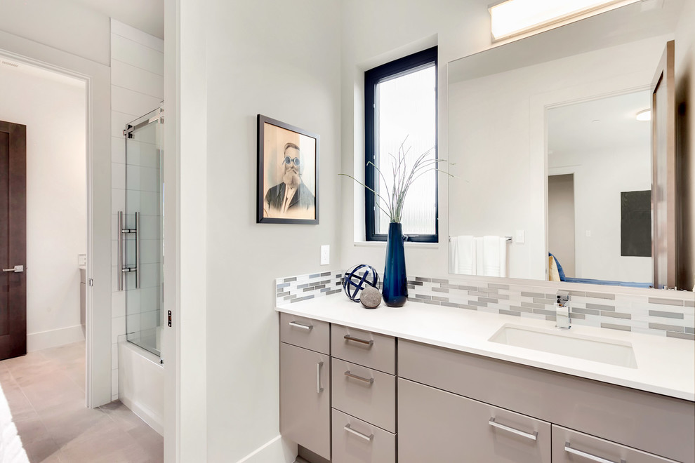 Inredning av ett modernt mellanstort badrum för barn, med släta luckor, grå skåp, en dusch/badkar-kombination, grå kakel, grå väggar, ett undermonterad handfat, bänkskiva i kvarts, grått golv och dusch med skjutdörr