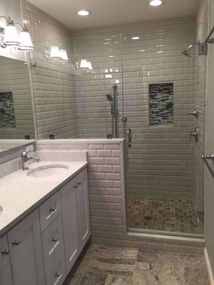 Modern inredning av ett mellanstort vit vitt badrum med dusch, med skåp i shakerstil, vita skåp, en toalettstol med hel cisternkåpa, grå kakel, tunnelbanekakel, grå väggar, travertin golv, ett undermonterad handfat, bänkskiva i kvartsit, grått golv, en dusch i en alkov och dusch med gångjärnsdörr