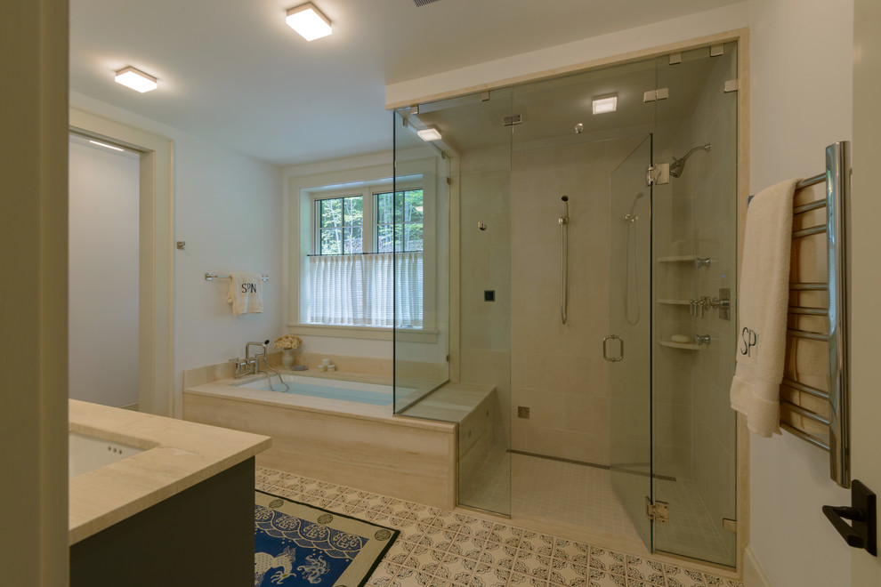 Cette photo montre une salle de bain principale chic de taille moyenne avec des portes de placard grises, un placard avec porte à panneau encastré, une baignoire encastrée, une douche d'angle, un carrelage beige, des carreaux de porcelaine, un lavabo encastré, une cabine de douche à porte battante, un plan de toilette beige, un mur blanc, carreaux de ciment au sol et un sol multicolore.