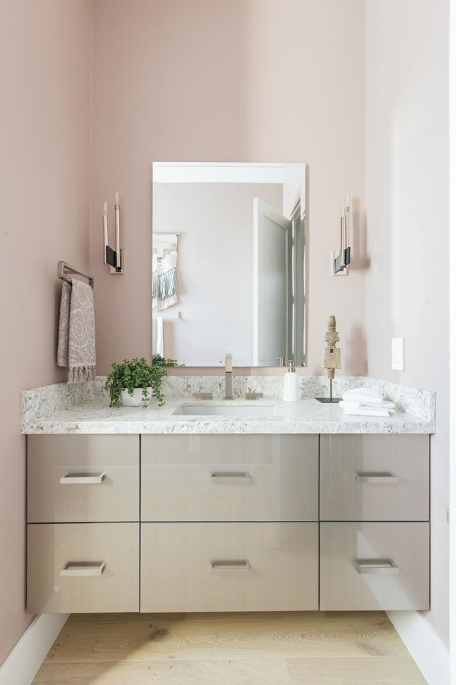 Inredning av ett modernt mellanstort grå grått badrum med dusch, med släta luckor, grå skåp, en toalettstol med hel cisternkåpa, rosa väggar, ljust trägolv, ett undermonterad handfat, granitbänkskiva och beiget golv