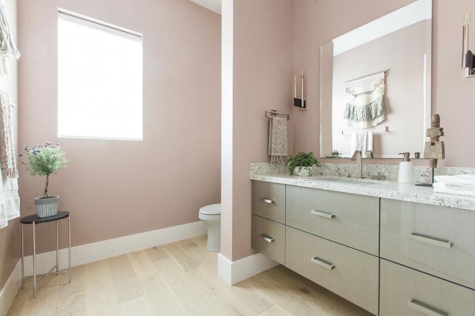 Imagen de cuarto de baño actual de tamaño medio con armarios con paneles lisos, puertas de armario grises, aseo y ducha, lavabo bajoencimera, encimera de granito, sanitario de una pieza, paredes rosas, suelo de madera clara y suelo beige