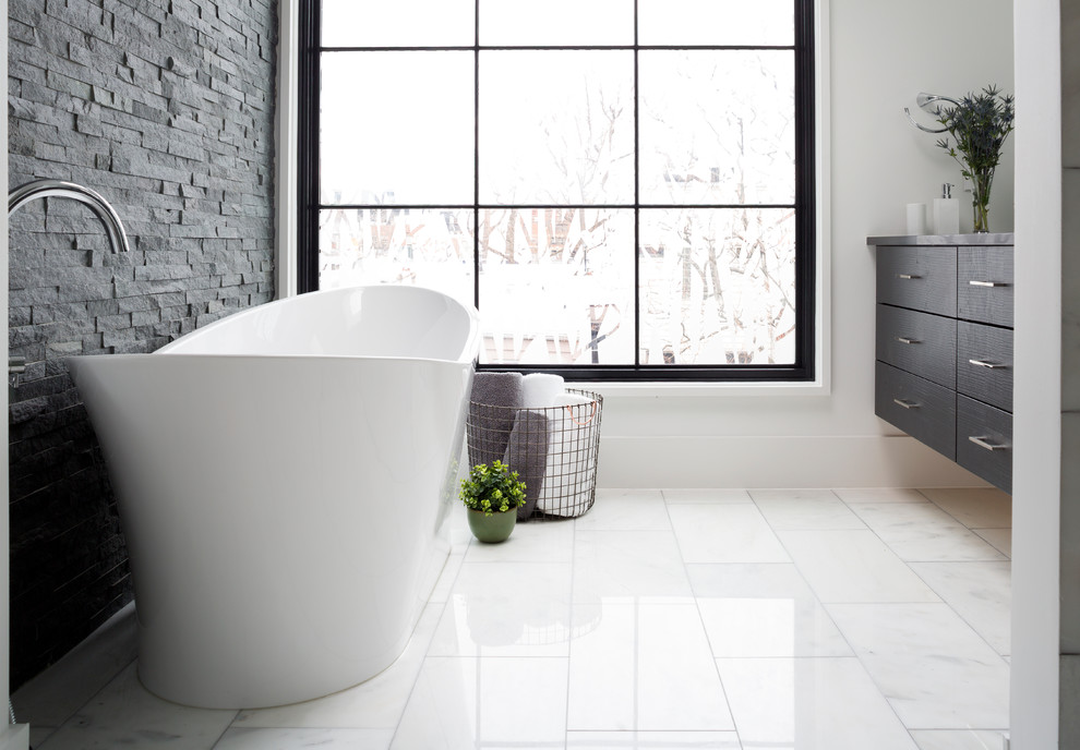 На фото: большая главная ванная комната в современном стиле с плоскими фасадами, серыми фасадами, отдельно стоящей ванной, угловым душем, унитазом-моноблоком, серой плиткой, плиткой из сланца, белыми стенами, мраморным полом, врезной раковиной, столешницей из искусственного камня, белым полом и душем с распашными дверями