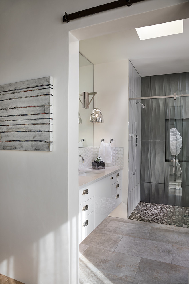 Medium sized modern shower room bathroom in Albuquerque with flat-panel cabinets, a built-in shower, a one-piece toilet, grey tiles, white walls, porcelain flooring, a submerged sink, solid surface worktops, grey floors, a hinged door, porcelain tiles and white cabinets.