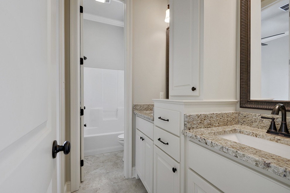 Photo of a small classic family bathroom in New Orleans with raised-panel cabinets, white cabinets, a built-in bath, a shower/bath combination, a two-piece toilet, beige tiles, ceramic tiles, beige walls, ceramic flooring, a submerged sink, granite worktops, beige floors and a shower curtain.