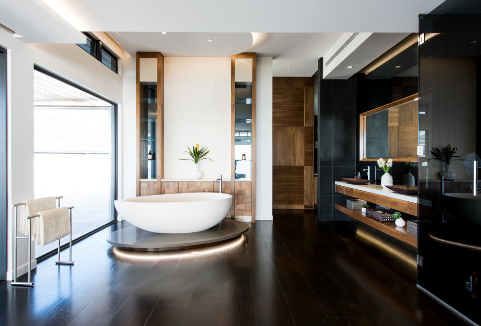 Источник вдохновения для домашнего уюта: главная ванная комната в современном стиле с открытыми фасадами, темными деревянными фасадами, отдельно стоящей ванной, черной плиткой, белыми стенами, настольной раковиной, коричневым полом и белой столешницей