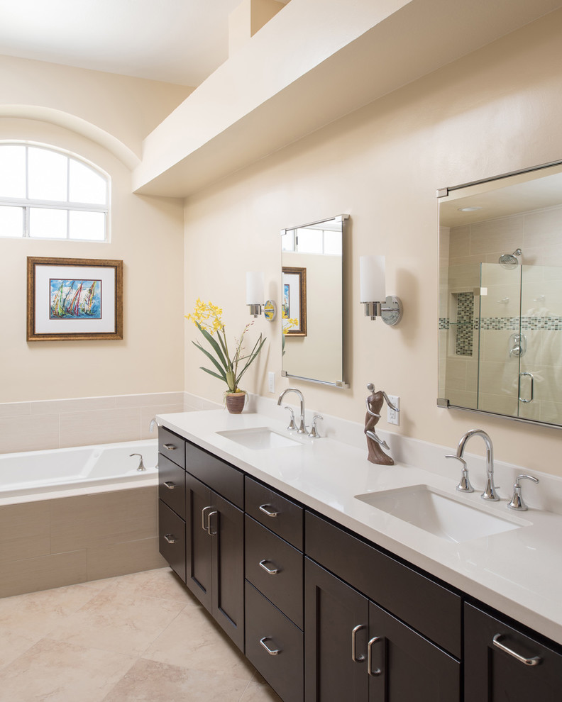 This is an example of a large mediterranean ensuite bathroom in San Diego with raised-panel cabinets, dark wood cabinets, a built-in bath, a corner shower, a two-piece toilet, beige tiles, porcelain tiles, beige walls, ceramic flooring, a submerged sink, engineered stone worktops, beige floors and a hinged door.