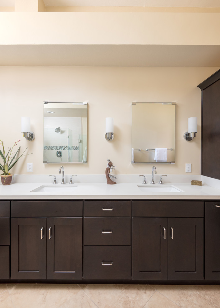 Inspiration for a large mediterranean master beige tile and porcelain tile ceramic tile and beige floor bathroom remodel in San Diego with raised-panel cabinets, dark wood cabinets, a two-piece toilet, beige walls, an undermount sink, quartz countertops and a hinged shower door