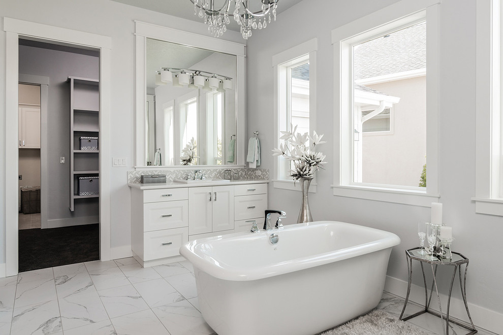 Ejemplo de cuarto de baño tradicional renovado con armarios con paneles empotrados, puertas de armario blancas, bañera exenta, paredes grises, lavabo encastrado, suelo blanco y encimeras blancas