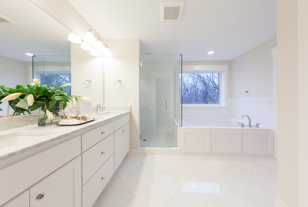 Photo of a large traditional ensuite bathroom in Minneapolis with shaker cabinets, white cabinets, a built-in bath, a corner shower, a two-piece toilet, white tiles, metro tiles, beige walls, porcelain flooring, a submerged sink, marble worktops, white floors and a hinged door.