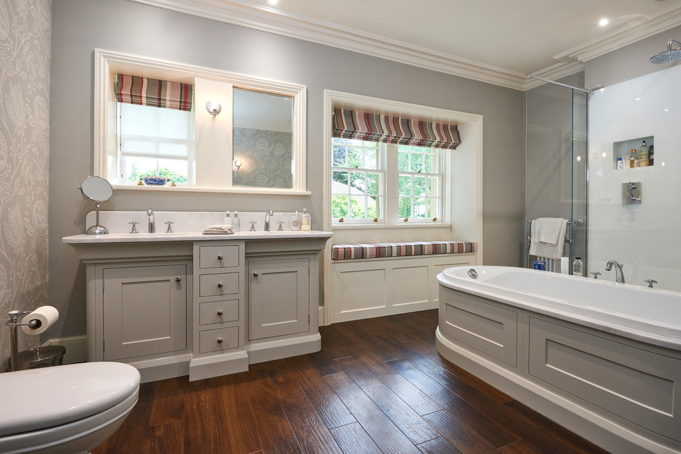 Classic ensuite bathroom in Other with shaker cabinets, grey cabinets, a built-in bath, a corner shower, white tiles, grey walls, a submerged sink, brown floors and a hinged door.