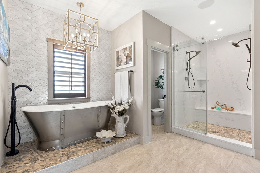На фото: главная ванная комната в стиле кантри с отдельно стоящей ванной, душем в нише, раздельным унитазом, белой плиткой, бежевыми стенами, бежевым полом и душем с раздвижными дверями с