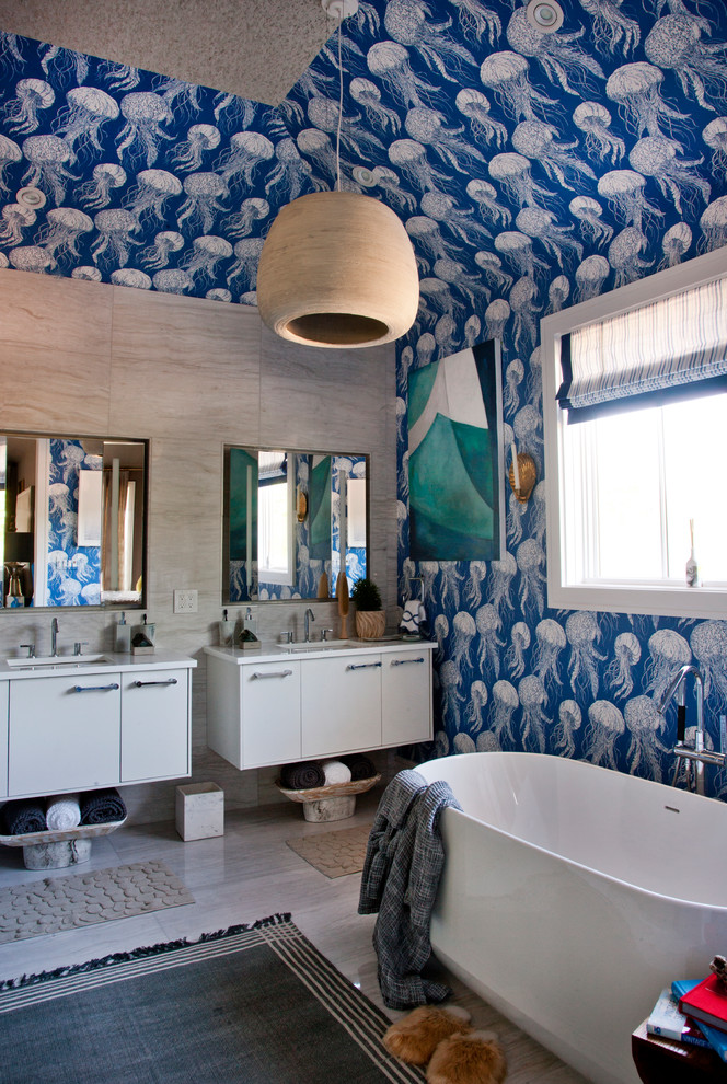 Foto di una stanza da bagno padronale costiera con ante lisce, ante bianche, vasca freestanding, pareti blu, lavabo sospeso e top bianco