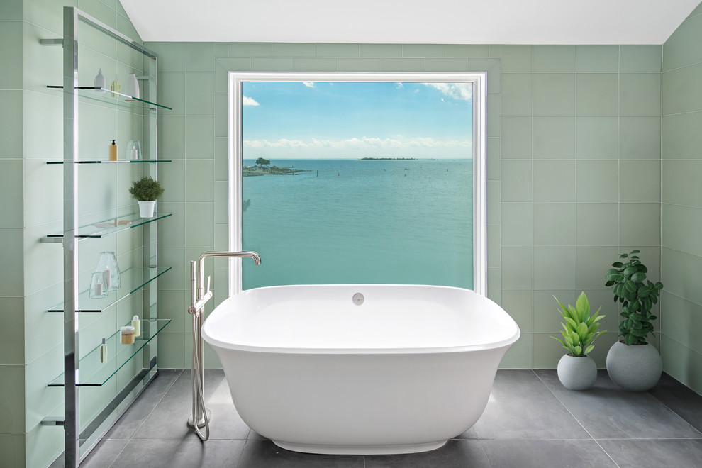 Пример оригинального дизайна: ванная комната в морском стиле с отдельно стоящей ванной, зеленой плиткой, стеклянной плиткой и серым полом