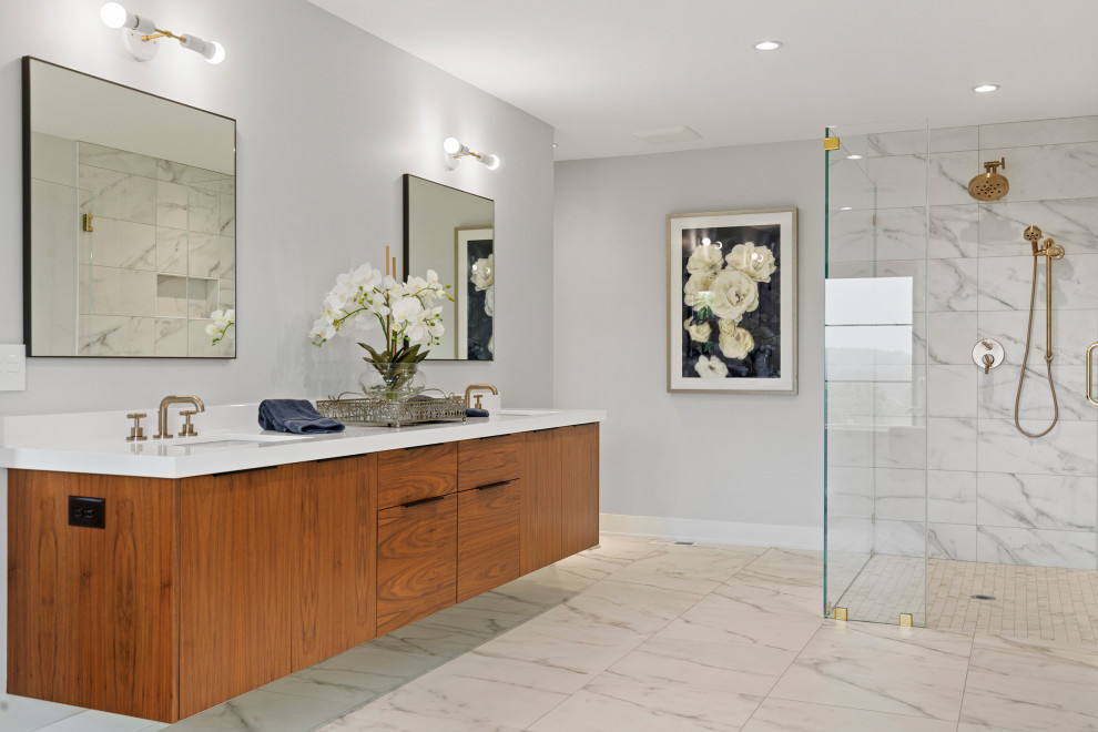 This is an example of an expansive contemporary ensuite bathroom in Minneapolis with flat-panel cabinets, medium wood cabinets, a built-in shower, grey tiles, marble tiles, grey walls, cement flooring, a submerged sink, engineered stone worktops, grey floors, a hinged door and white worktops.