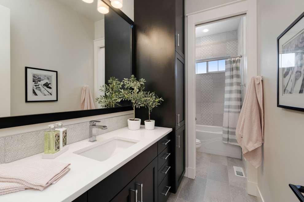 Example of a mid-sized country gray tile, white tile and ceramic tile cement tile floor and gray floor bathroom design in Boise with recessed-panel cabinets, black cabinets, gray walls, an undermount sink, quartz countertops and white countertops