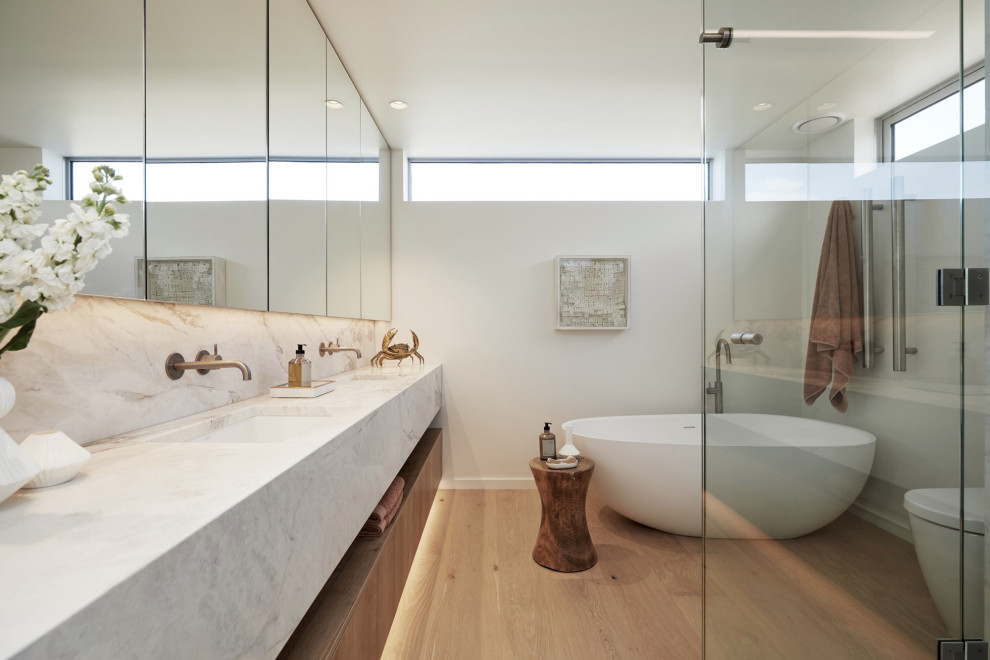 Inspiration för ett mellanstort maritimt en-suite badrum, med släta luckor, skåp i mellenmörkt trä, ett fristående badkar, mellanmörkt trägolv, ett undermonterad handfat och marmorbänkskiva