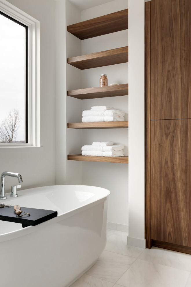 Contemporary ensuite bathroom in Minneapolis with brown cabinets, a freestanding bath, marble flooring, a submerged sink, marble worktops, white floors, a hinged door, white worktops, an enclosed toilet, double sinks and a floating vanity unit.