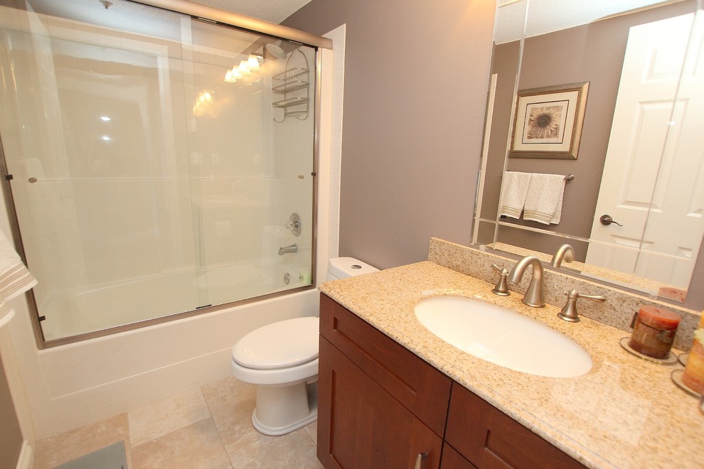 Modelo de cuarto de baño contemporáneo pequeño con lavabo bajoencimera, armarios con rebordes decorativos, encimera de granito y combinación de ducha y bañera