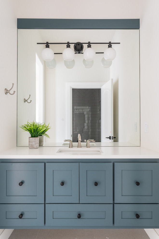 Modelo de cuarto de baño único y flotante clásico renovado con armarios estilo shaker, puertas de armario azules, paredes blancas, lavabo bajoencimera y encimeras blancas