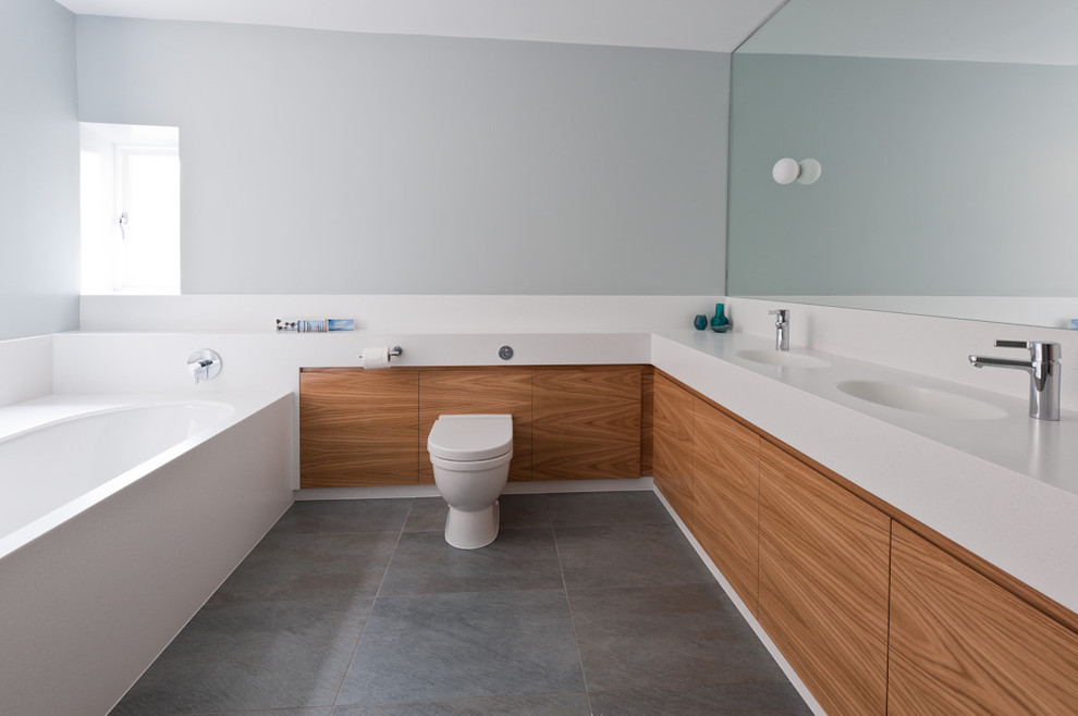 Modernes Badezimmer mit flächenbündigen Schrankfronten und hellbraunen Holzschränken in Sonstige