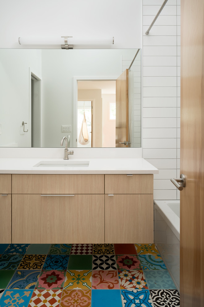 Пример оригинального дизайна: детская ванная комната в современном стиле с плоскими фасадами, светлыми деревянными фасадами, ванной в нише, душем в нише, керамической плиткой, полом из цементной плитки, врезной раковиной, столешницей из искусственного кварца, шторкой для ванной, белой плиткой, белыми стенами и разноцветным полом