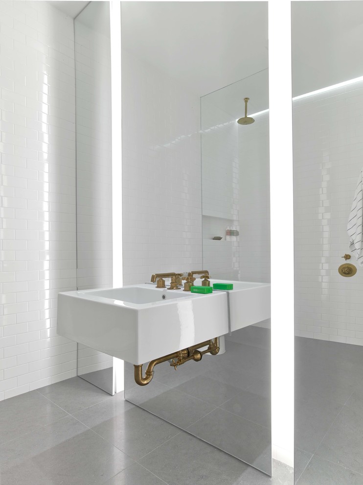 This is an example of a modern bathroom in New York with white tiles, metro tiles, a wall-mounted sink and grey floors.