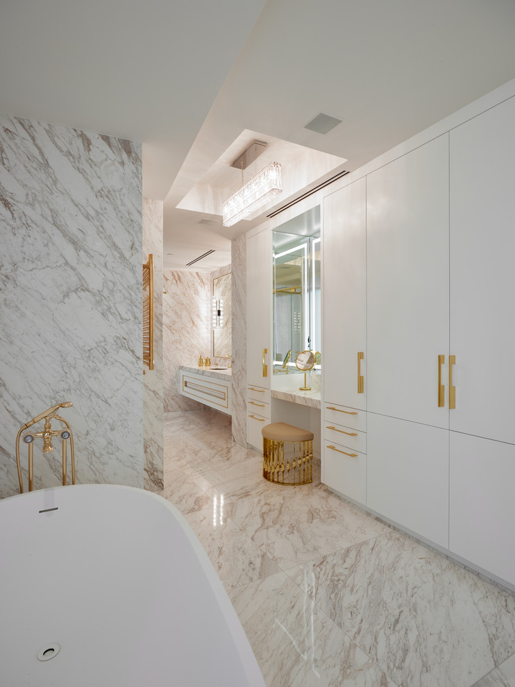 Cette image montre une très grande salle de bain principale design avec des portes de placard blanches, un carrelage blanc, des dalles de pierre et un plan de toilette en marbre.