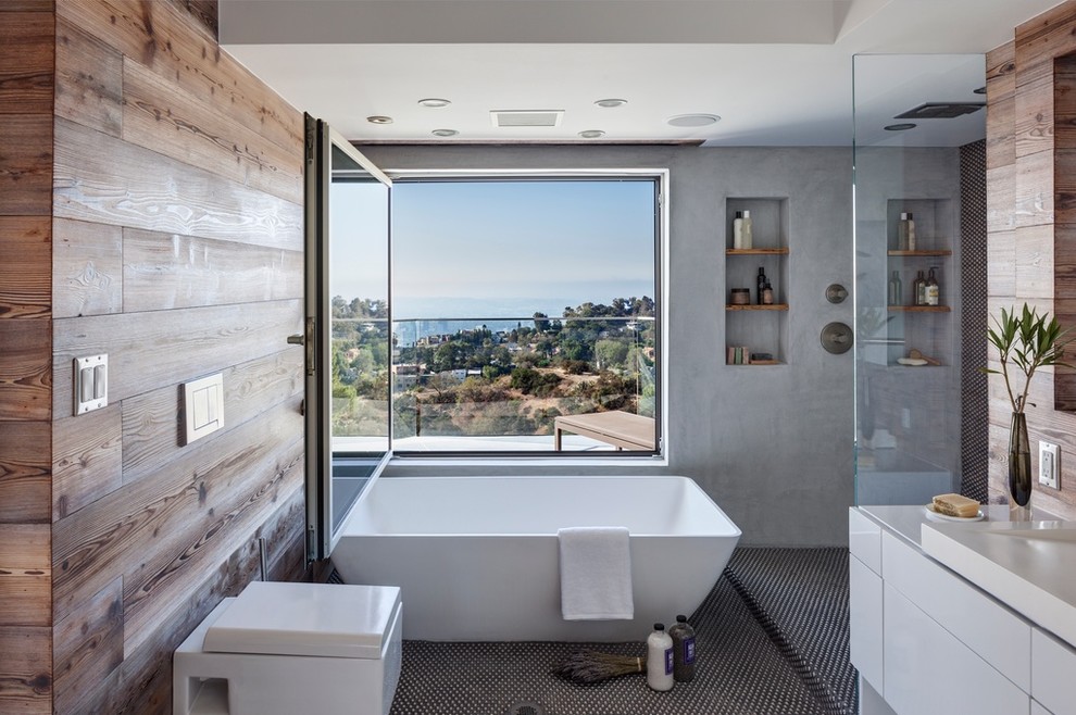 ロサンゼルスにあるコンテンポラリースタイルのおしゃれな浴室 (フラットパネル扉のキャビネット、白いキャビネット、置き型浴槽、グレーのタイル、モザイクタイル) の写真