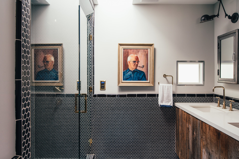 Diseño de cuarto de baño principal actual con armarios con paneles lisos, puertas de armario con efecto envejecido, ducha empotrada, baldosas y/o azulejos negros, suelo de baldosas tipo guijarro, paredes grises, lavabo bajoencimera, ducha con puerta con bisagras y encimeras beige