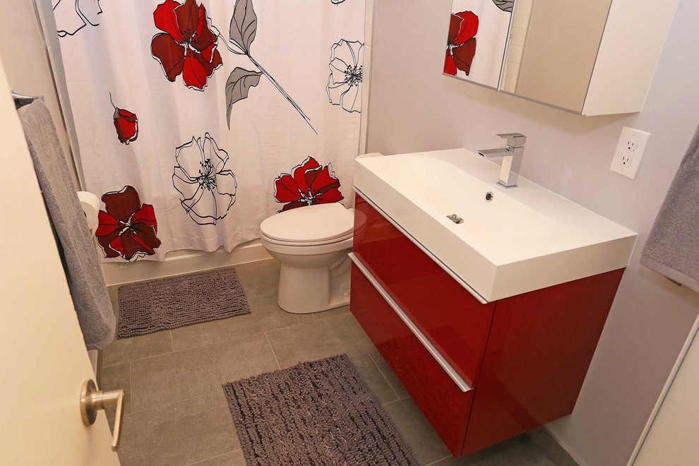 Idéer för att renovera ett mellanstort funkis en-suite badrum, med släta luckor, röda skåp, ett platsbyggt badkar, en dusch/badkar-kombination, en toalettstol med hel cisternkåpa, grå kakel, cementkakel, grå väggar, klinkergolv i keramik, ett integrerad handfat och bänkskiva i kalksten