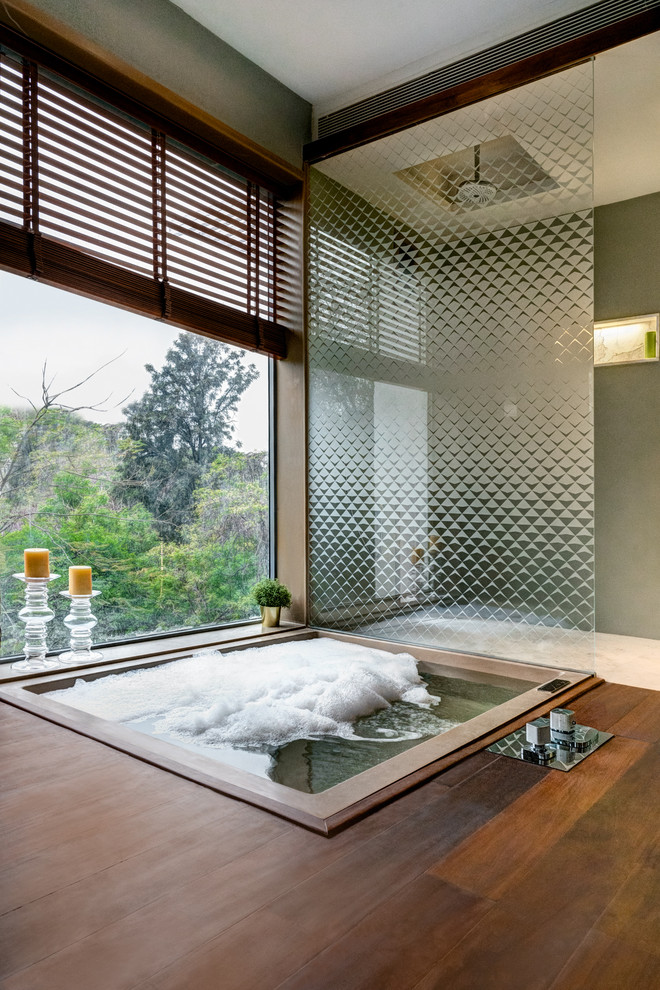 Modelo de cuarto de baño principal de estilo zen con jacuzzi, ducha a ras de suelo, paredes grises, ducha abierta, suelo de madera oscura y suelo marrón