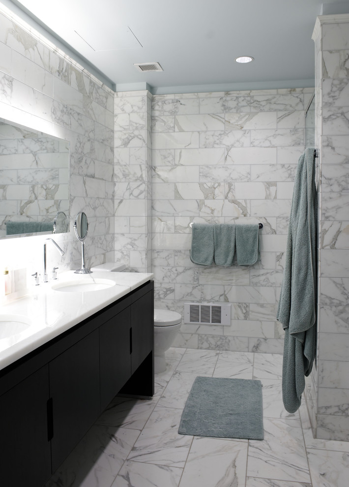 ニューヨークにあるコンテンポラリースタイルのおしゃれな浴室 (アンダーカウンター洗面器、フラットパネル扉のキャビネット、黒いキャビネット、大理石の洗面台、白いタイル、大理石の床、大理石タイル) の写真