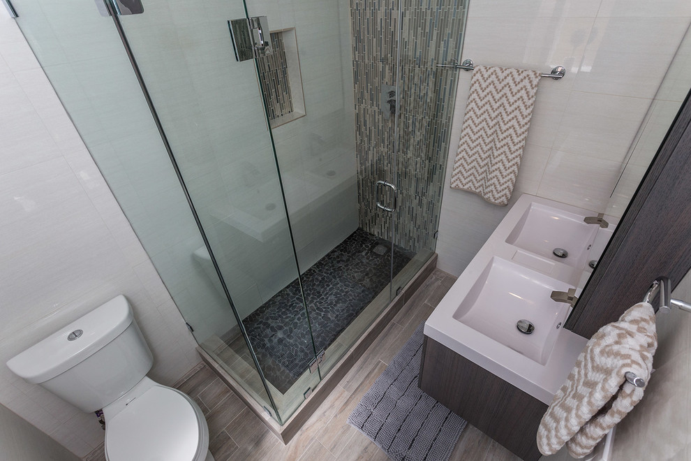 Small trendy 3/4 white tile and porcelain tile porcelain tile and brown floor corner shower photo in Miami with flat-panel cabinets, dark wood cabinets, a two-piece toilet, white walls, an undermount sink and a hinged shower door