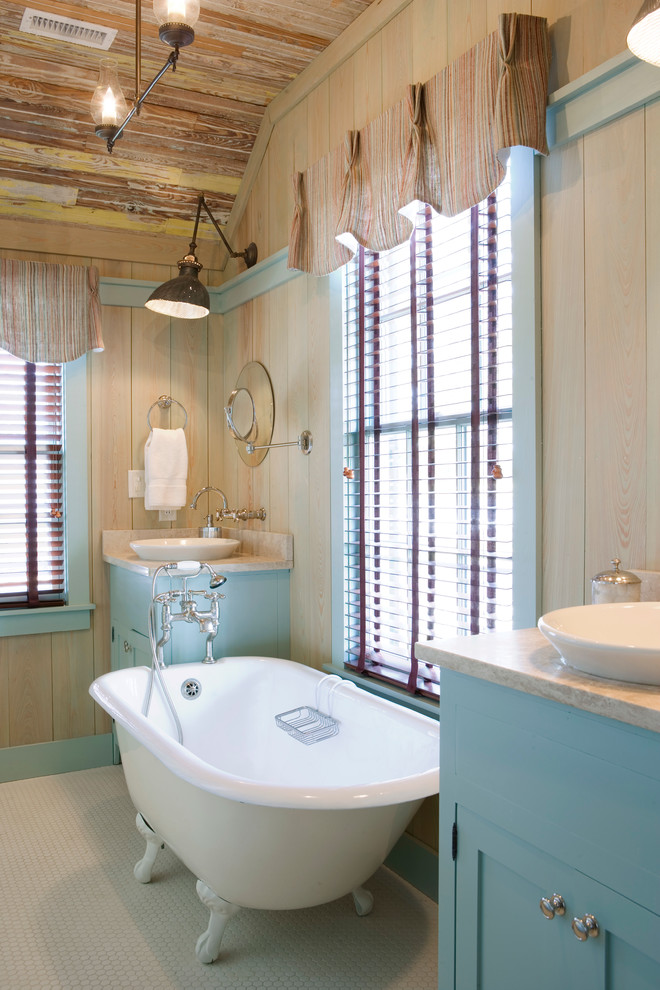 This is an example of a country bathroom in Atlanta with a claw-foot bath, a vessel sink and blue cabinets.