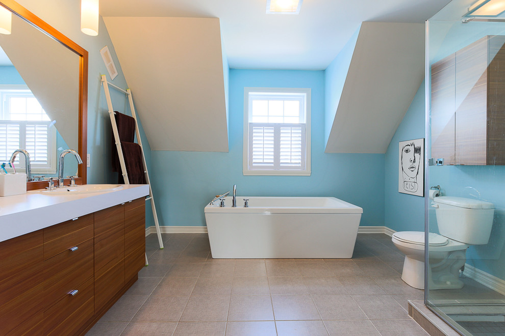 Пример оригинального дизайна: большая главная ванная комната в современном стиле с накладной раковиной, плоскими фасадами, фасадами цвета дерева среднего тона, столешницей из ламината, отдельно стоящей ванной, угловым душем, раздельным унитазом, серой плиткой, керамической плиткой, синими стенами и полом из керамической плитки