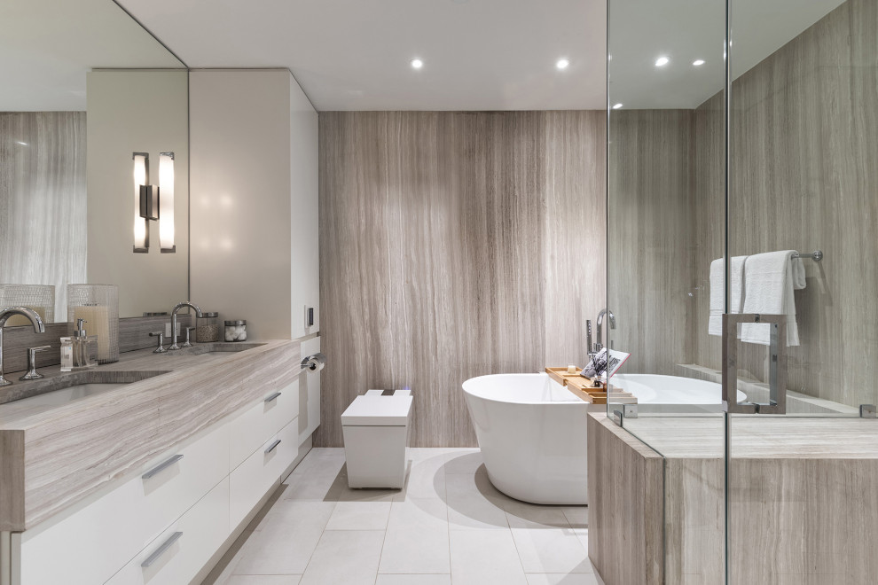 Идея дизайна: ванная комната в современном стиле с плоскими фасадами, белыми фасадами, отдельно стоящей ванной, угловым душем, серой плиткой, врезной раковиной, белым полом, серой столешницей, тумбой под две раковины и встроенной тумбой