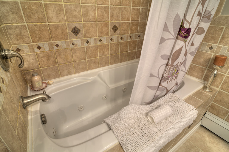 Inspiration pour une douche en alcôve vintage avec un bain bouillonnant, un carrelage beige, des carreaux de céramique, un mur gris et un sol en carrelage de céramique.