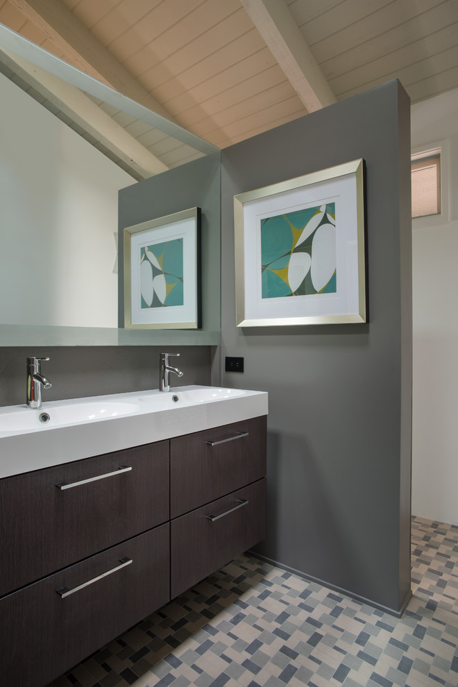 Photo of a small midcentury ensuite bathroom in Kansas City with flat-panel cabinets, dark wood cabinets, a built-in shower, a one-piece toilet, multi-coloured tiles, ceramic tiles, grey walls, ceramic flooring and solid surface worktops.